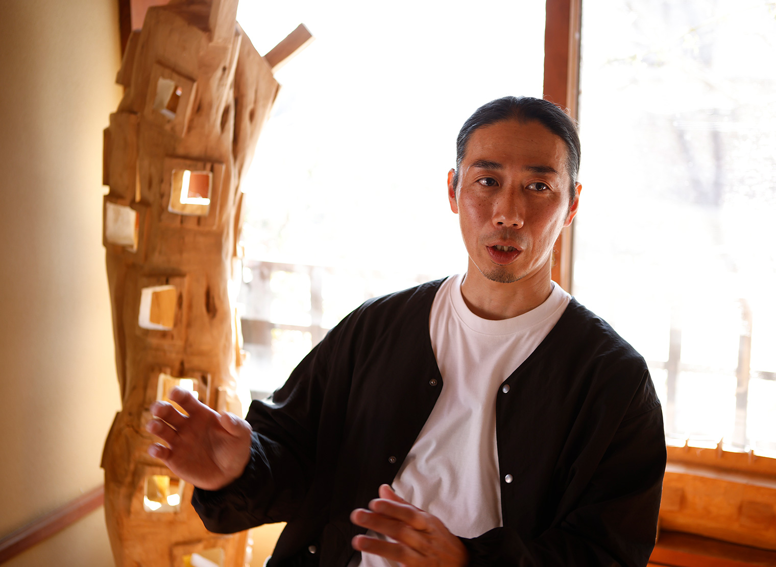 象鯨彫刻家具の作品を前に話をする里氏。撮影: Hiroyuki Matsuzaki (INTO THE LIGHT)